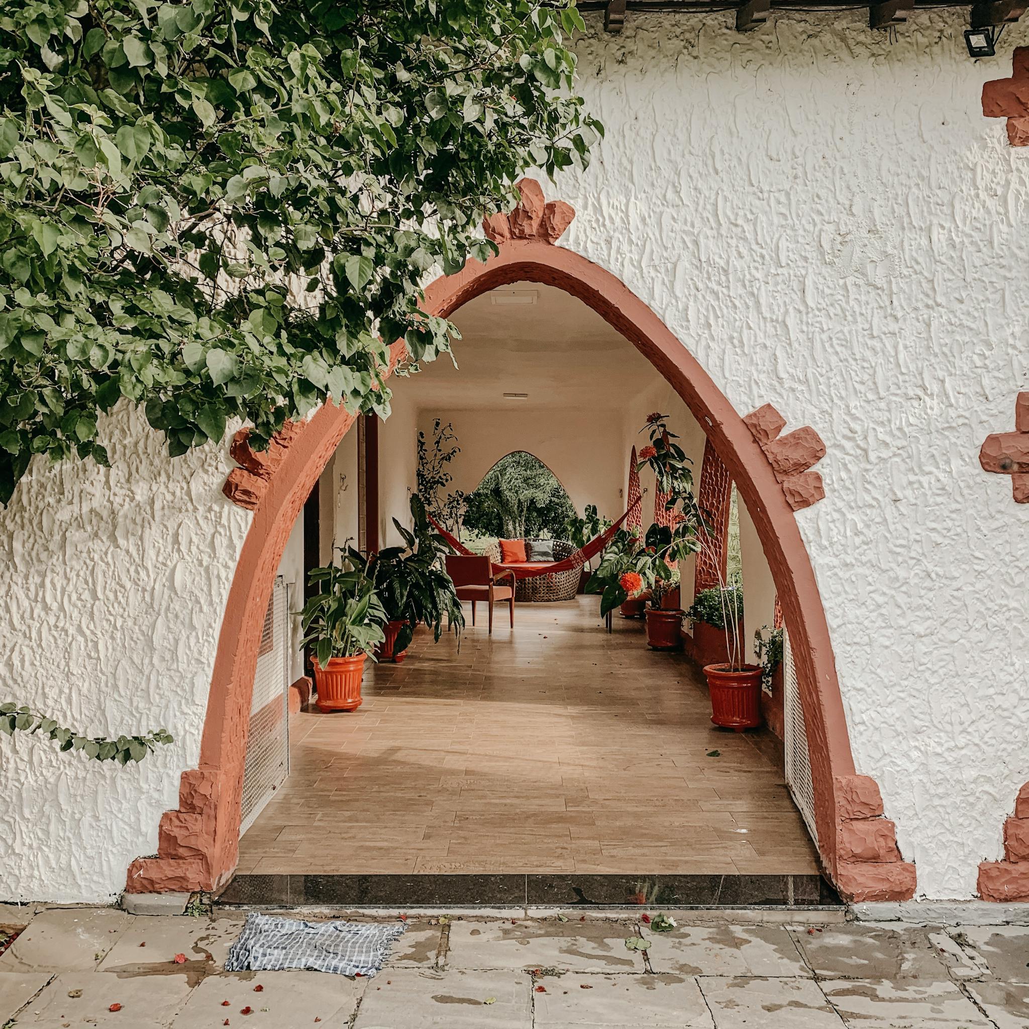 Cozy home entrance featuring an elegant red archway, vibrant greenery, and rustic designs, perfect for a serene lifestyle.