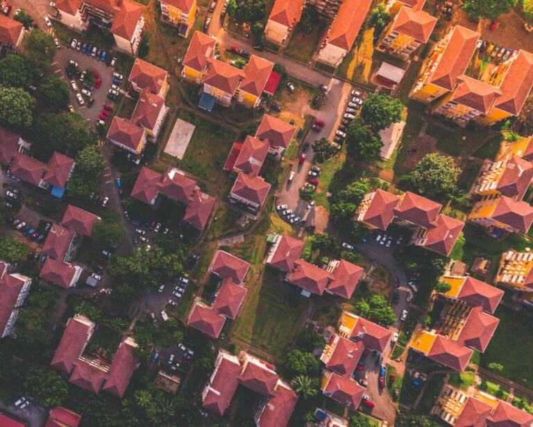 Stunning aerial view of urban residential neighborhood with houses and greenery during sunset.