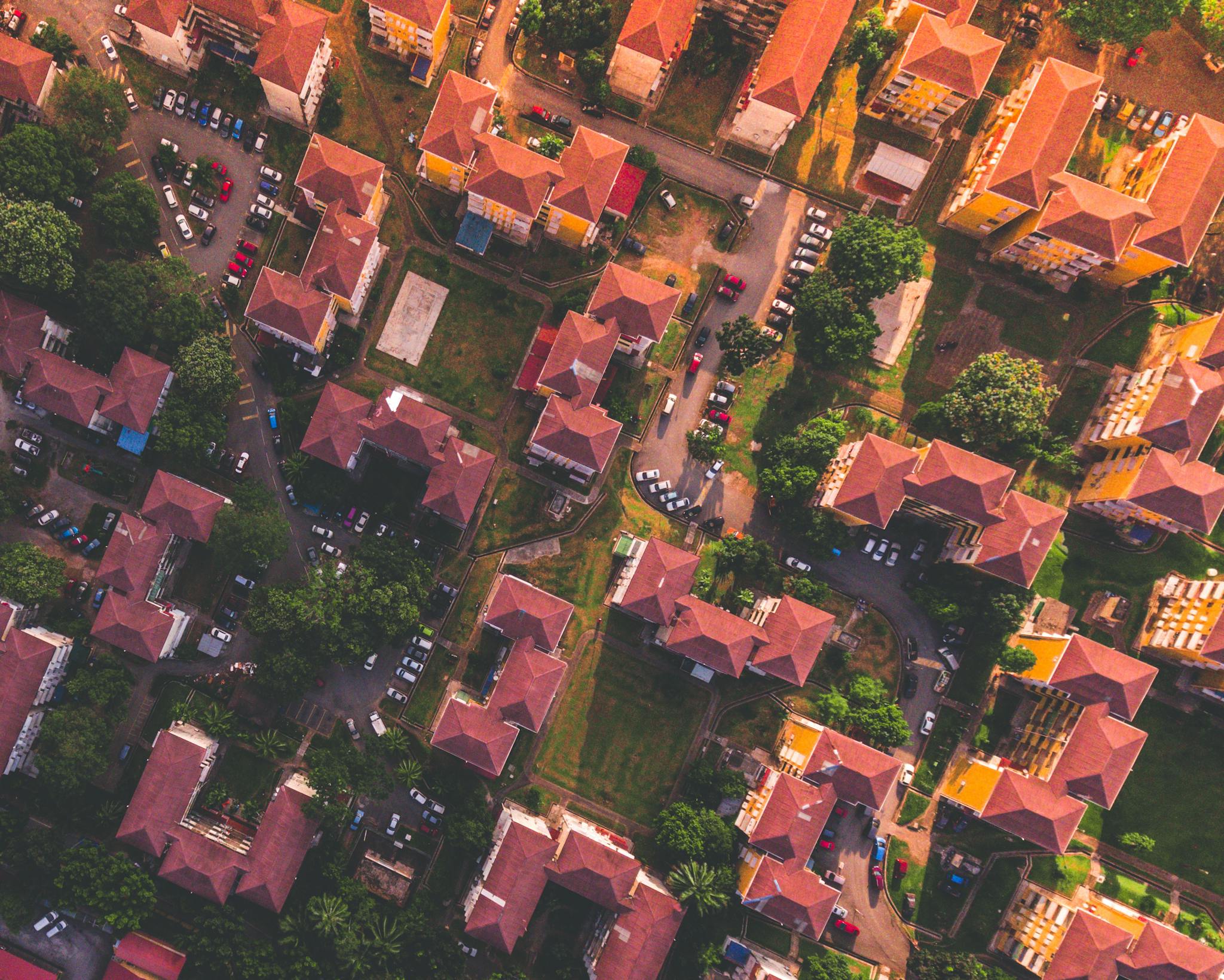 Stunning aerial view of urban residential neighborhood with houses and greenery during sunset.